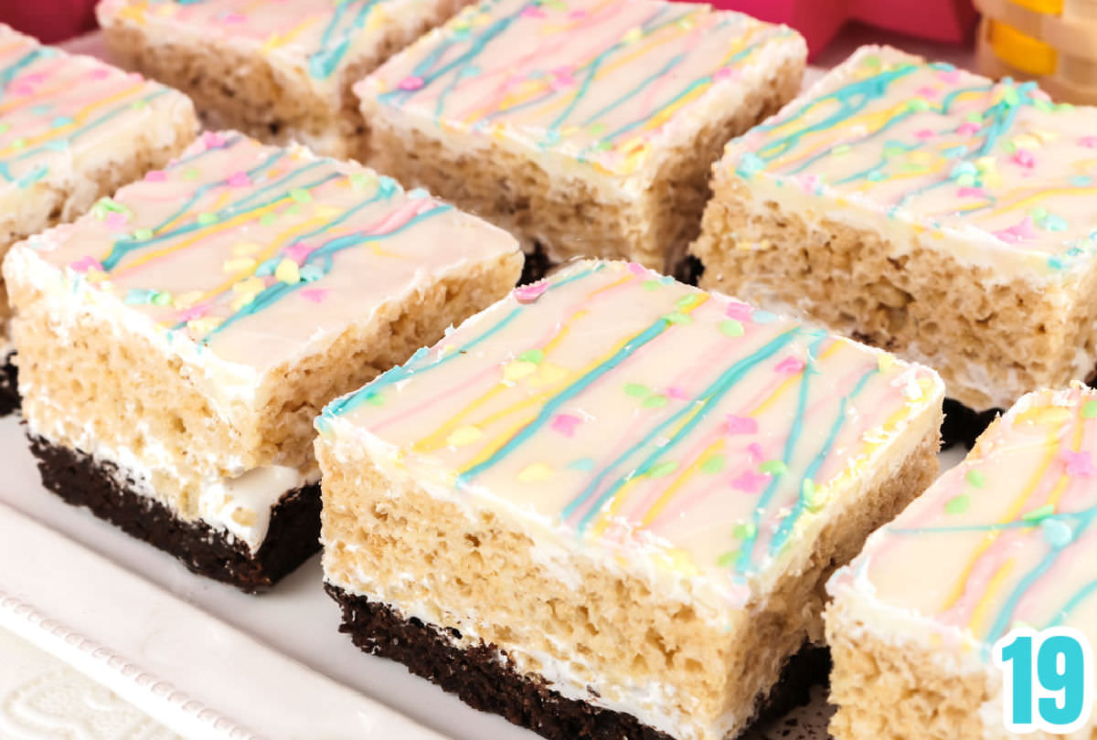 Eight Brownie Rice Krispie Treats on a white serving platter sitting on a white surface.