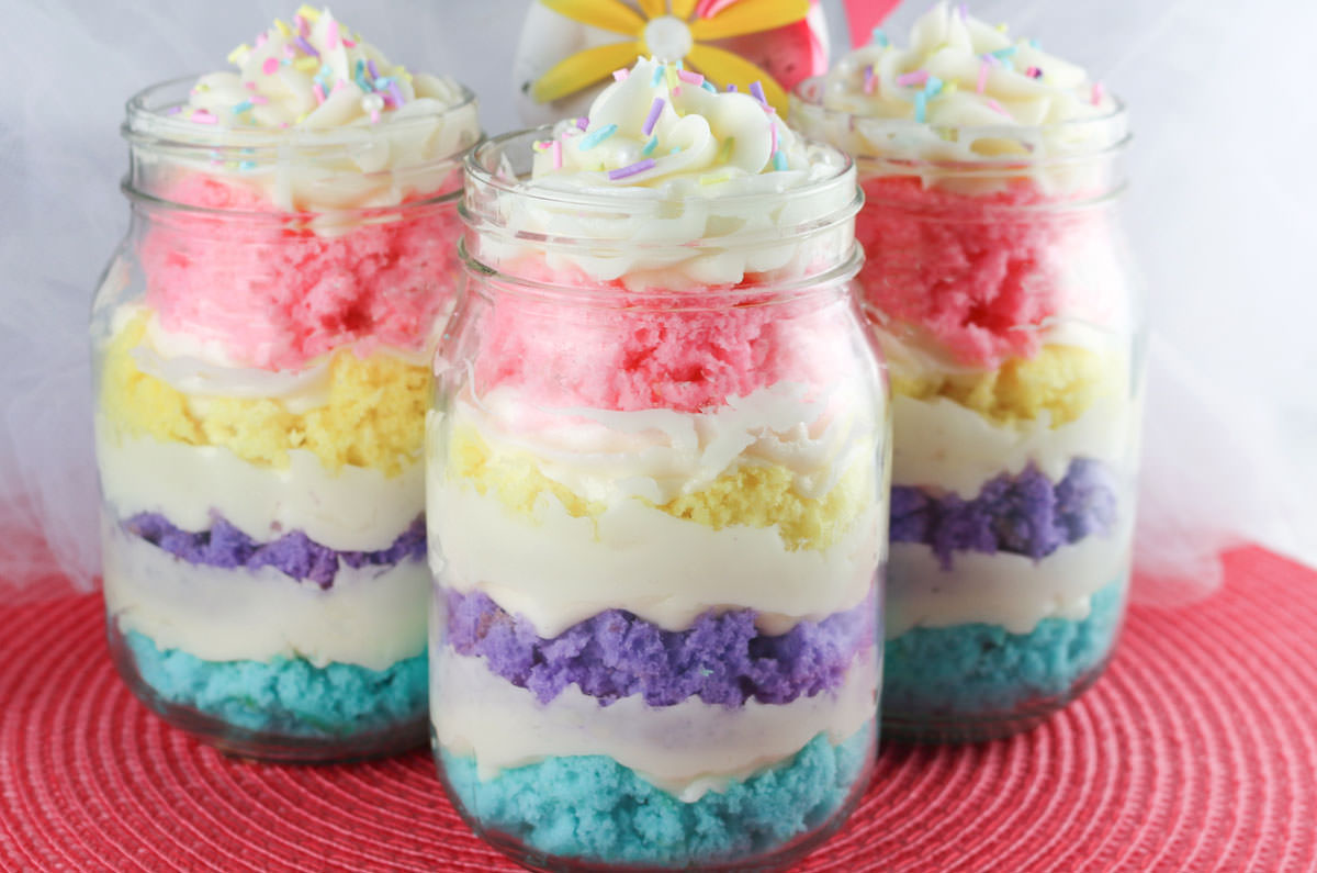 Close up on three Springtime Cupcakes in a Jar sitting on a pink placemat in front of white tulle.