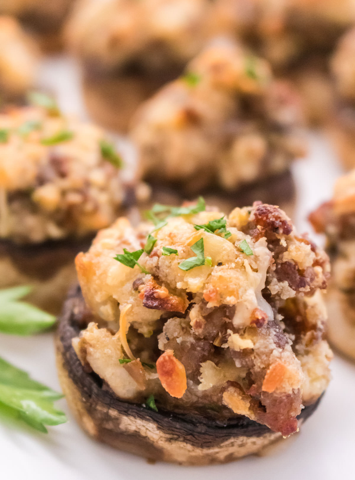 Closeup on a Stuffed Mushroom appetizer sitting on a white serving platter.