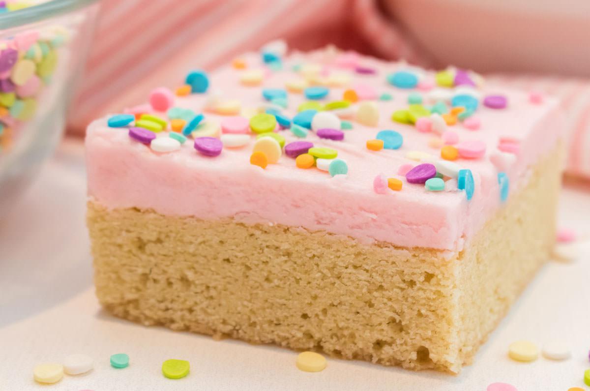 Closeup of a single The Best Sugar Cookie Bar, frosted with pink homemade buttercream frosting and sprinkles.