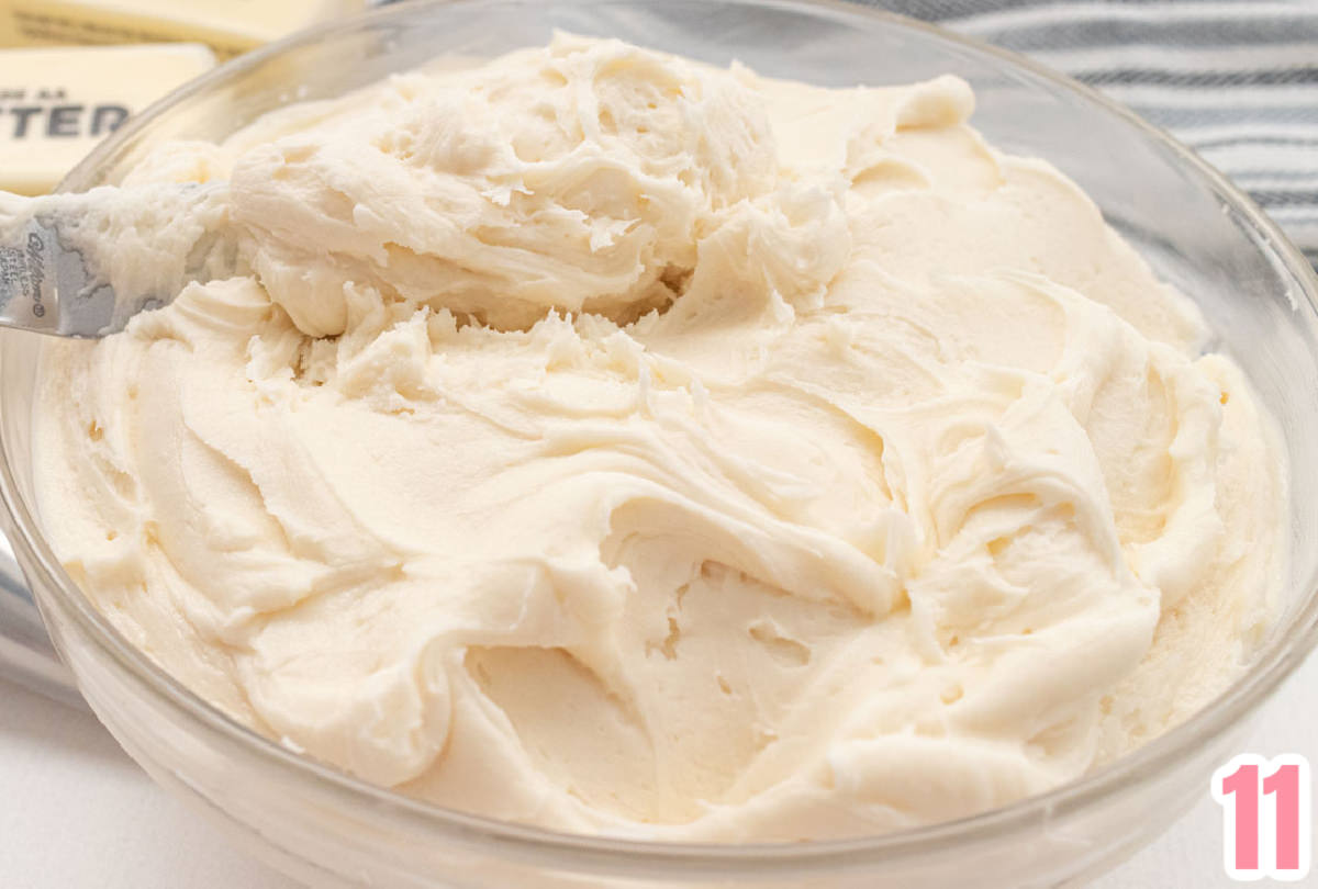 Closeup on a glass bowl filled with creamy homemade buttercream frosting.