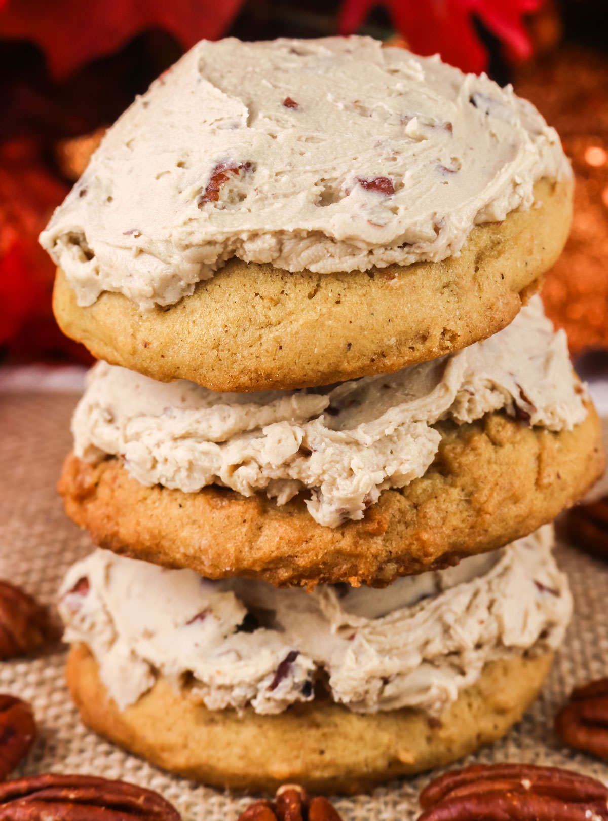 Closeup on a stack of three Sweet Potato Cookies frosted with Maple Pecan Frosting surrounded by Pecans.