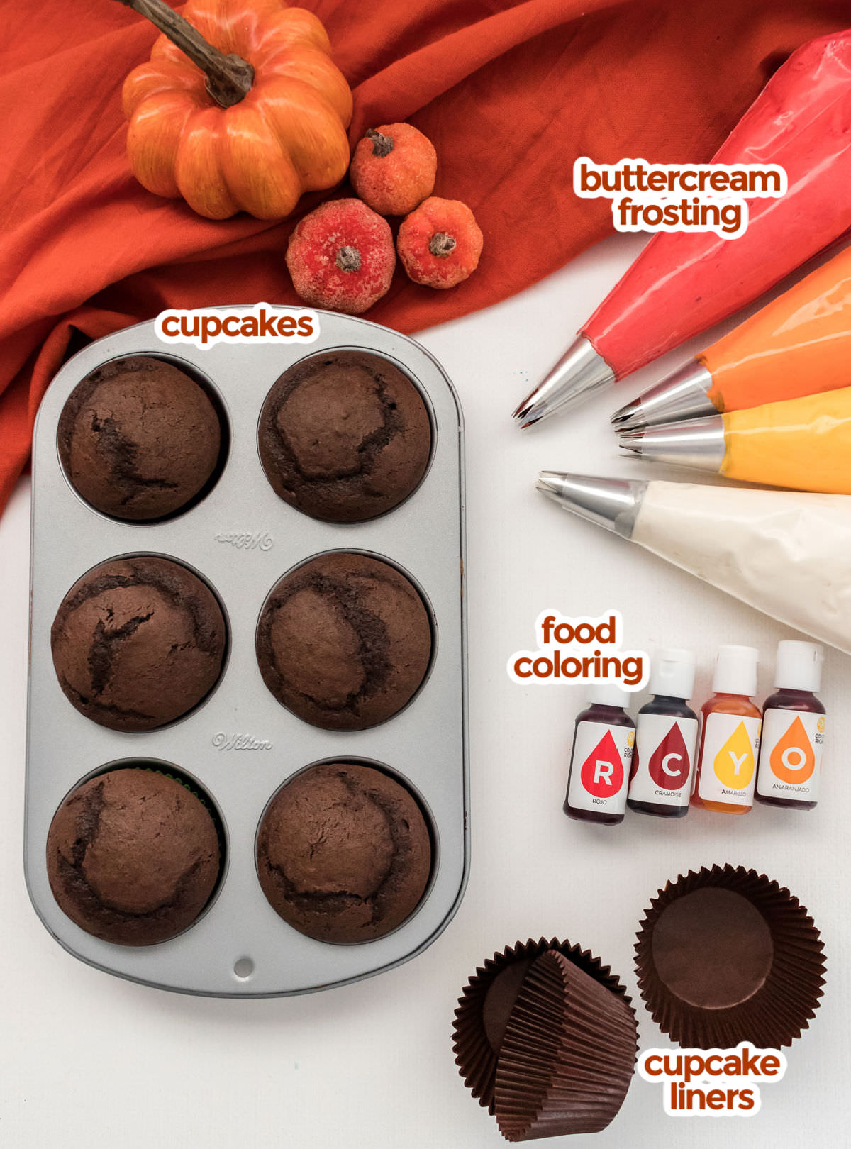 All the ingredients you will need to make Harvest Thanksgiving Cupcakes including chocolate cupcakes, buttercream frosting, food coloring and cupcake liners.