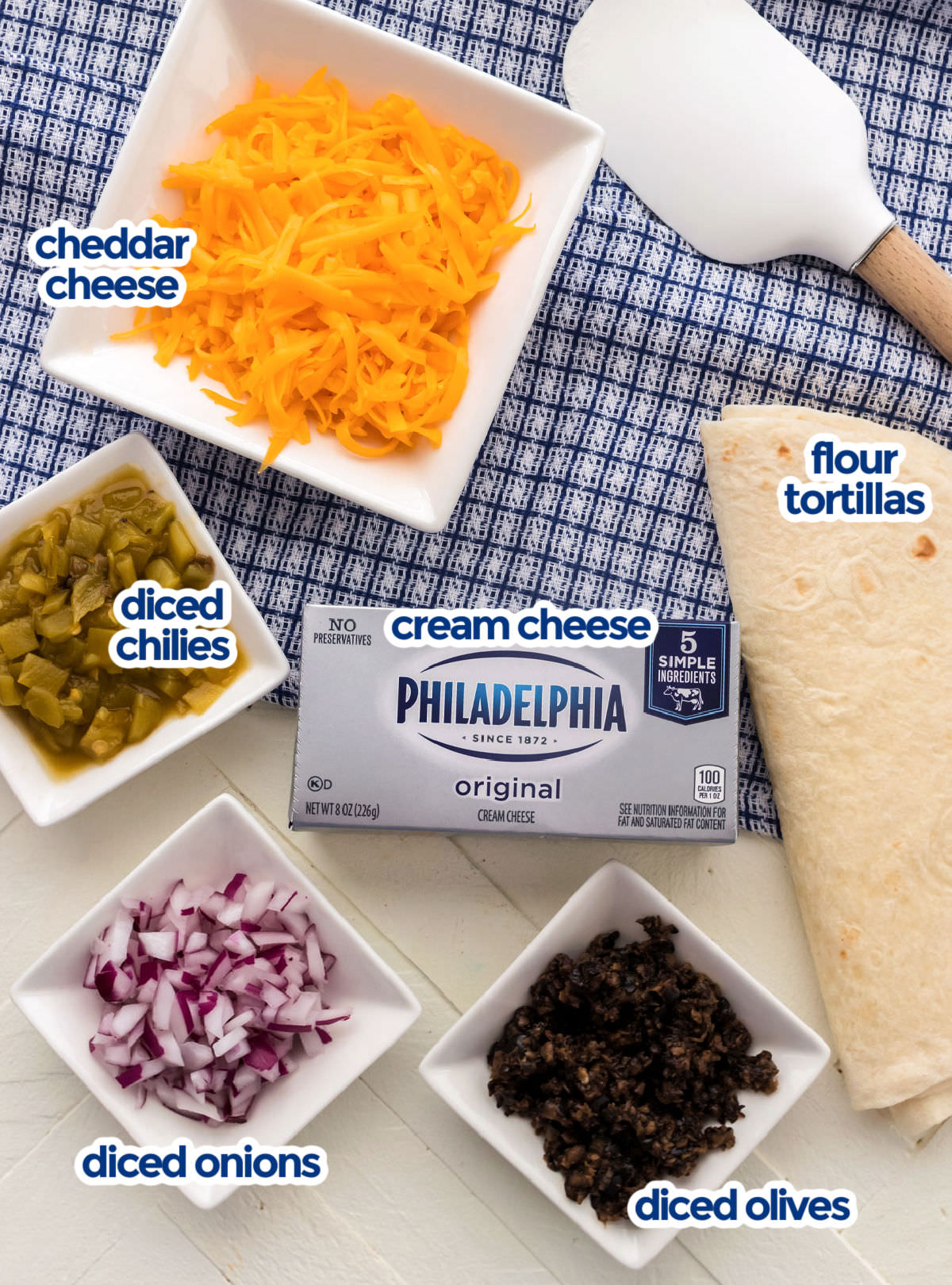 All the ingredients you will need to make Tortilla Pinwheels including cheese, cream cheese, flour tortillas, diced chilies, red onion and olives.