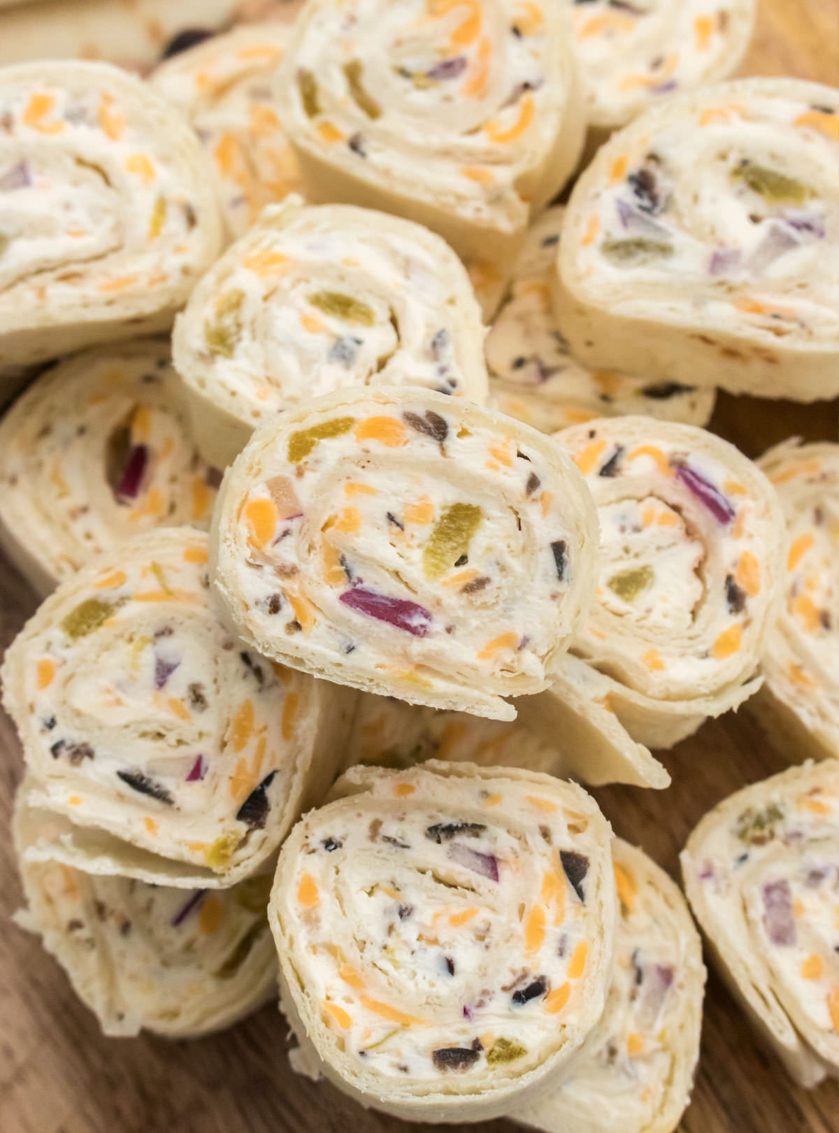 Closeup on a stack of Tortilla Pinwheels sitting on a cutting board.