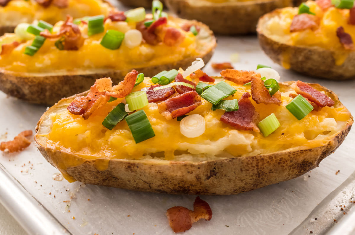 Closeup on a Twice Baked Potato sitting on a parchment paper covered cookie sheet.