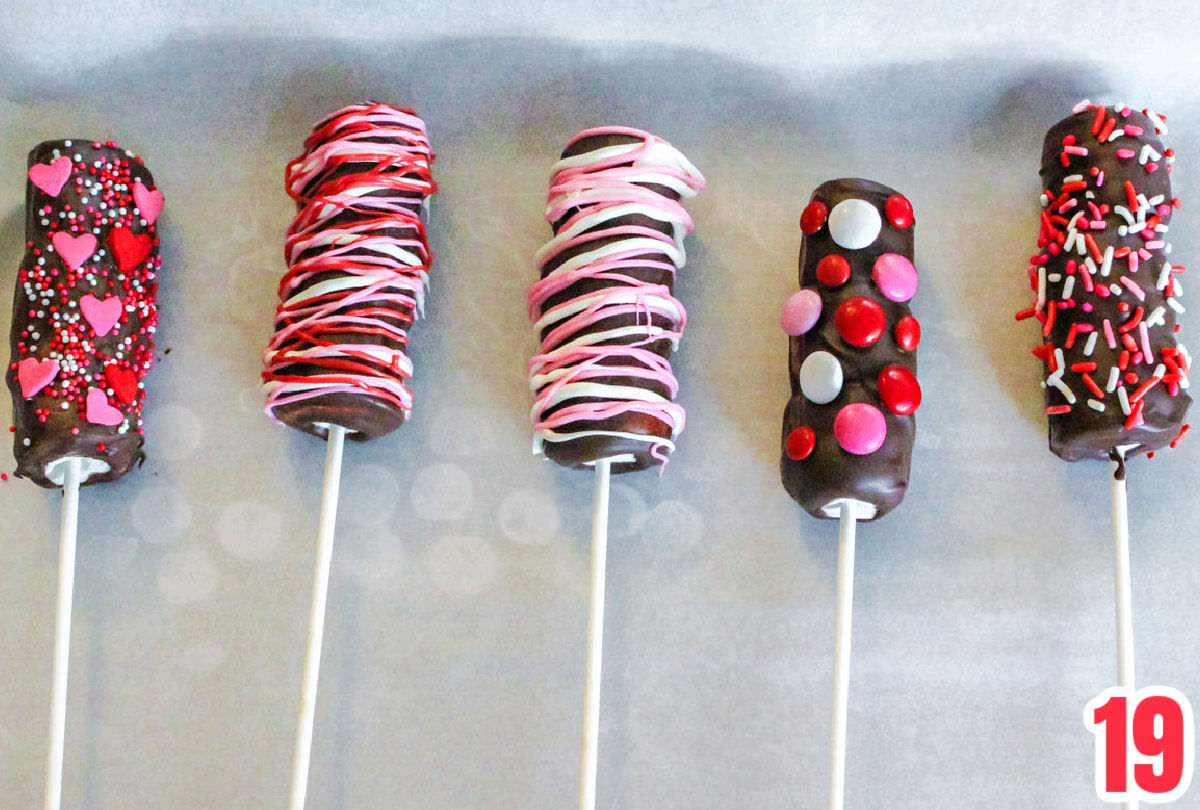 Close up of decorated Marshmallow Wands drying and hardening on a parchment paper covered cookie sheet.