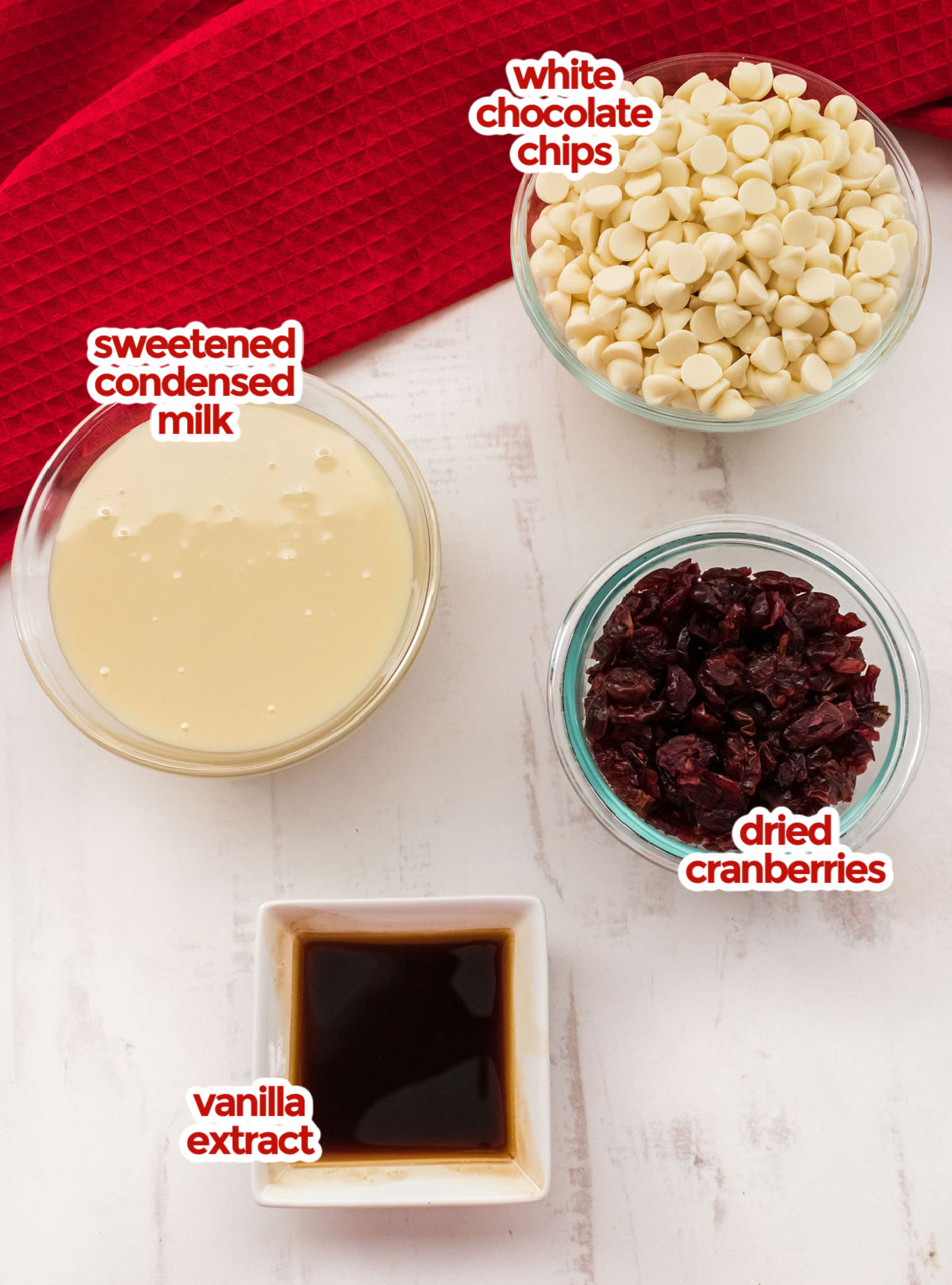 All the ingredients you will need to make White Chocolate Cranberry Fudge including White Chocolate Chips, Sweetened Condensed Milk, Dried Cranberries and Vanilla.
