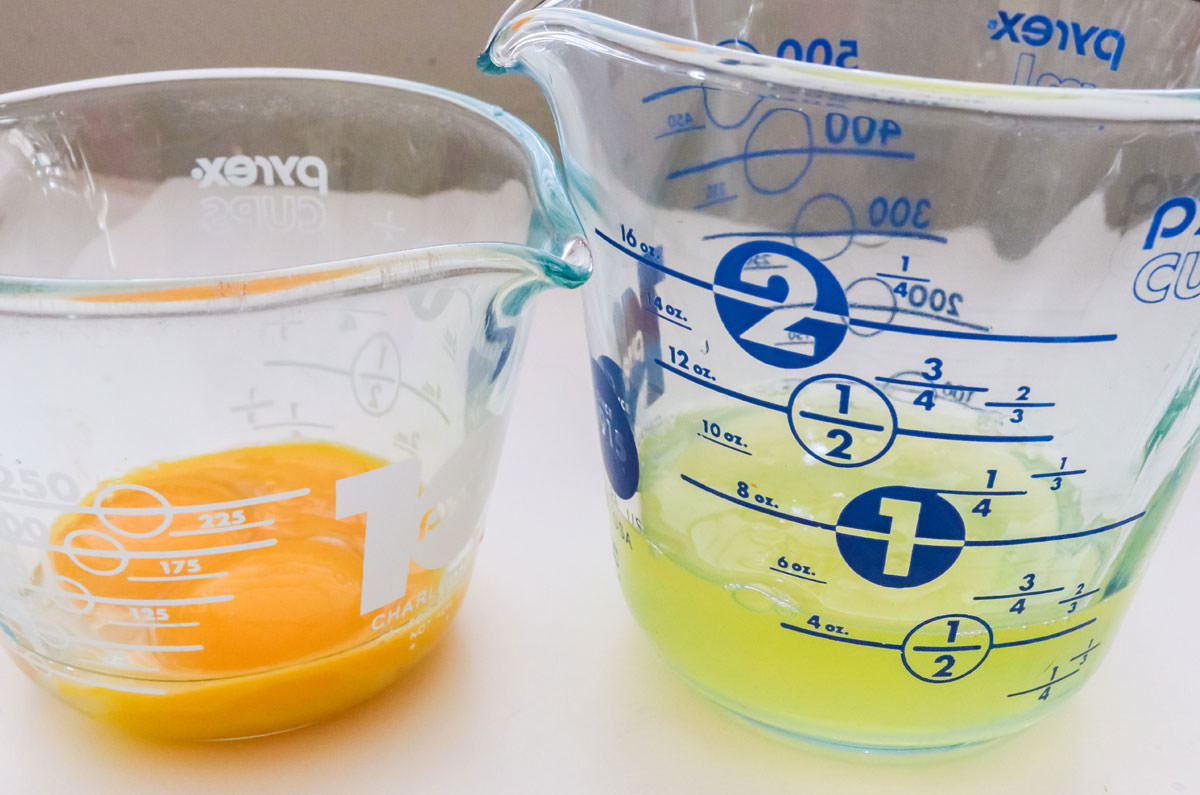 Two measuring cups, one filled with cooking oil and the other filled with two unshelled eggs.